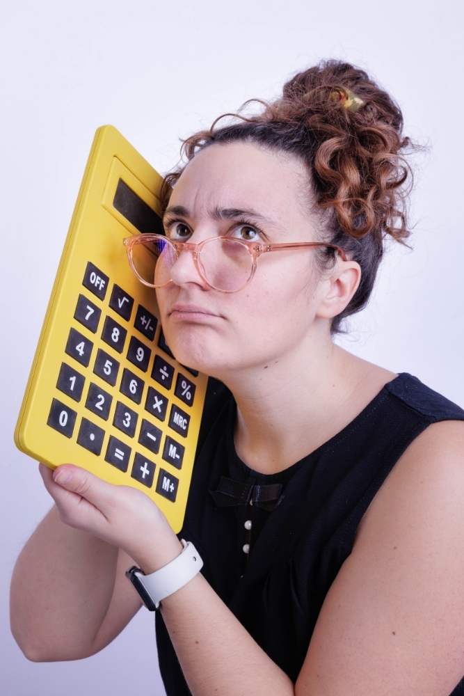 Assistante indépendante tenant une calculatrice jaune avec une expression sérieuse