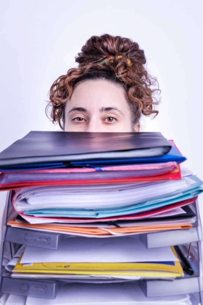 Assistante indépendante derrière une pile de dossiers à traiter