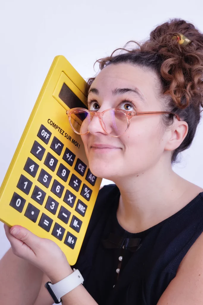 Assistante indépendante tenant une grande calculatrice jaune avec humour