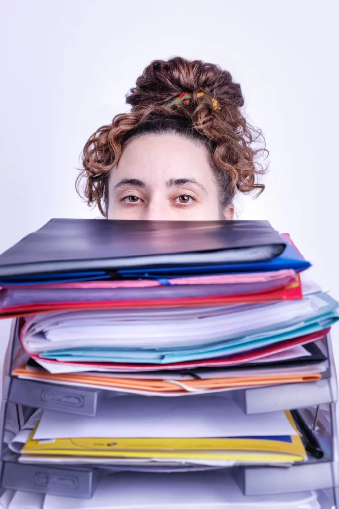 Assistante indépendante derrière une pile de dossiers à traiter