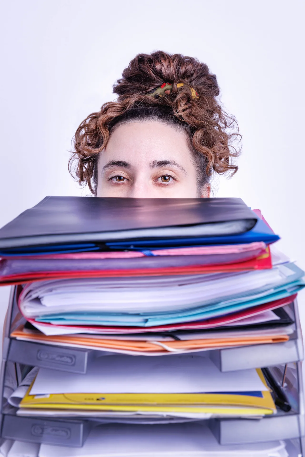 Assistante indépendante derrière une pile de dossiers à traiter
