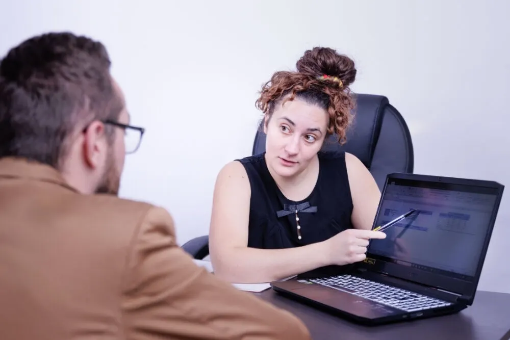 Assistante indépendante montrant des informations sur son ordinateur à un client