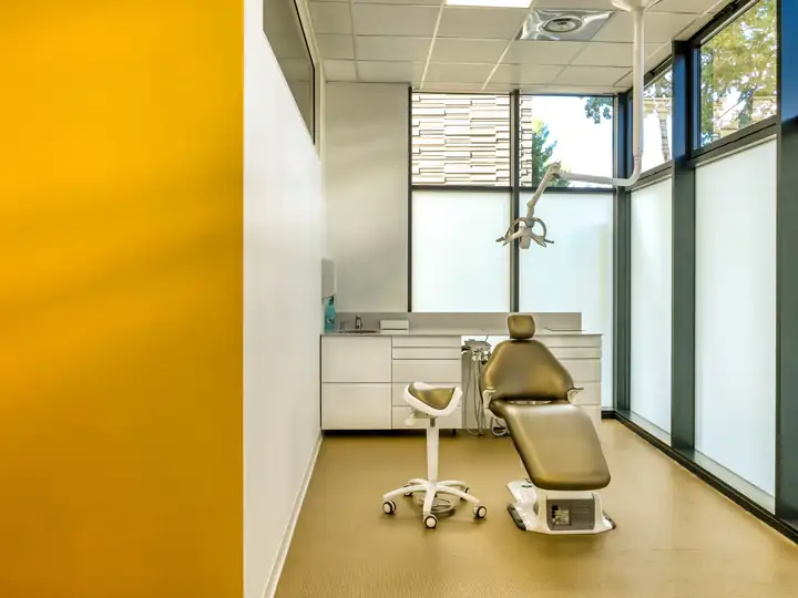 Cabinet dentaire lumineux avec fauteuil de soin et mur jaune